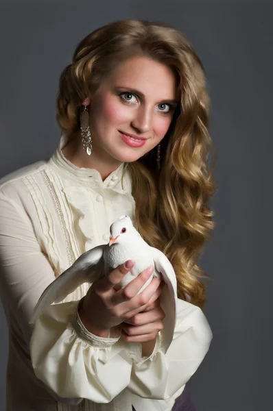 Beautiful woman with white dove on dark background — Stock Photo, Image