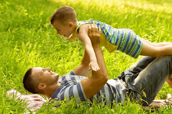 Far og sønn leker på grønn mark. – stockfoto