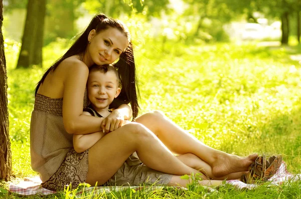 Mother and son siting on green field — Stock Photo, Image