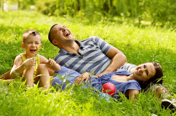 Happy family lying down in the garden — Stock Photo, Image