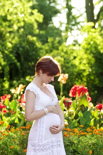 Krásná těhotná žena v zelené zahradě — Stock fotografie