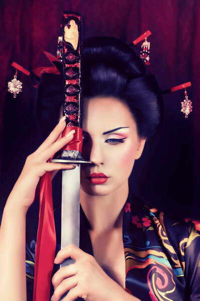 Beautiful geisha in kimono with samurai sword