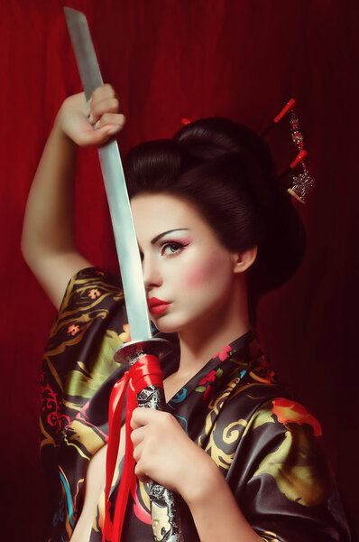 Beautiful geisha in kimono with samurai sword