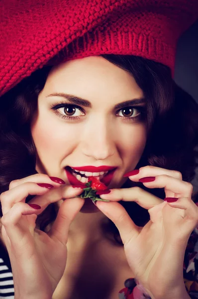 Giovane donna con fragola in berretto rosso — Foto Stock