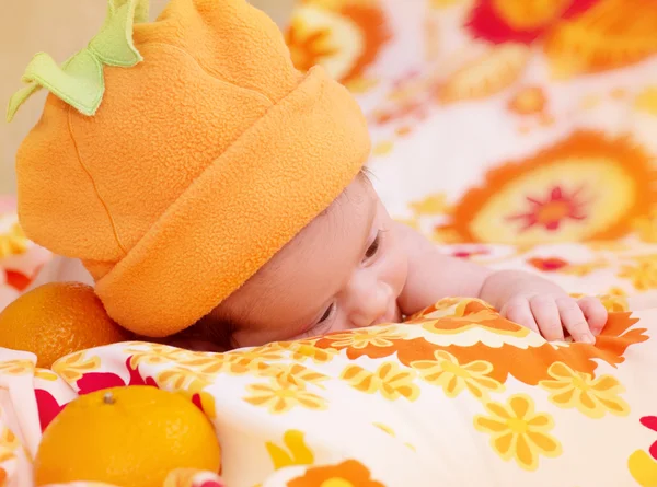 Nyfödd baby flicka i orange mössa med mandarin — Stockfoto