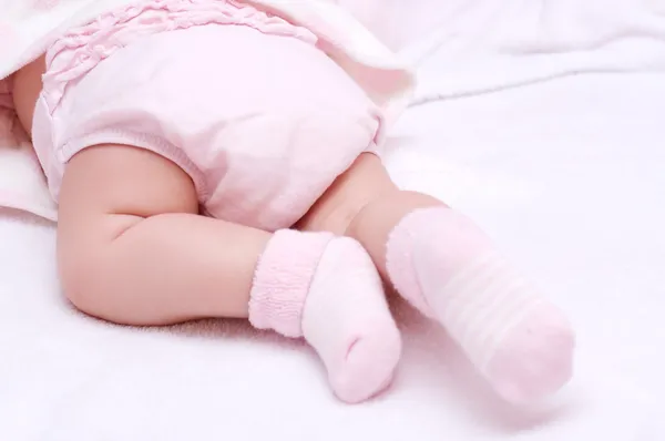 Bebé recién nacido pies de niña en calcetines rosados —  Fotos de Stock