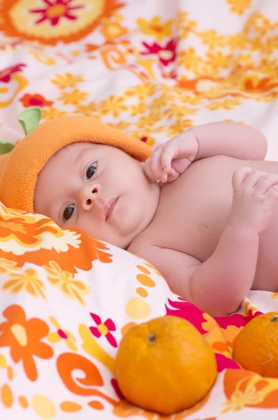 Newborn baby girl in orange hat with mandarin — Stock Photo, Image