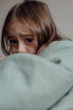 Savaşı durdurun. Ukrayna için dua et. Ukrayna 'nın tarafındayız. Battaniyenin altında korkmuş Ukraynalı bir çocuk. Kız hava saldırıları ve patlamaların seslerinden korkuyor. Zavallı çocuk üzüntü ve keder hissediyor, kötü şans ve keder sorunları.. 