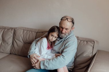 Savaşı durdurun. Ukraynalı endişeli orta yaşlı beyaz adam korkmuş küçük torunu destekliyor. Mutsuz, olgun büyükbaba ve küçük kız evde. Ukrayna için dua et. Ukrayna 'nın yanındayız..