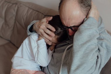 Savaşı durdurun. Ukraynalı endişeli orta yaşlı beyaz adam korkmuş küçük torunu destekliyor. Mutsuz, olgun büyükbaba ve küçük kız evde. Ukrayna için dua et. Ukrayna 'nın yanındayız..