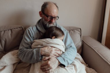 Savaşı durdurun. Ukraynalı endişeli orta yaşlı beyaz adam korkmuş küçük torunu destekliyor. Mutsuz, olgun büyükbaba ve küçük kız evde. Ukrayna için dua et. Ukrayna 'nın yanındayız..