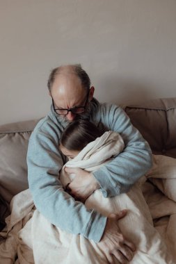 Savaşı durdurun. Ukraynalı endişeli orta yaşlı beyaz adam korkmuş küçük torunu destekliyor. Mutsuz, olgun büyükbaba ve küçük kız evde. Ukrayna için dua et. Ukrayna 'nın yanındayız..