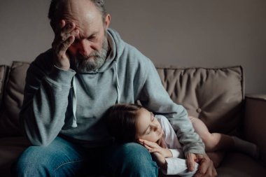 Savaşı durdurun. Ukraynalı endişeli orta yaşlı beyaz adam korkmuş küçük torunu destekliyor. Mutsuz, olgun büyükbaba ve küçük kız evde. Ukrayna için dua et. Ukrayna 'nın yanındayız..