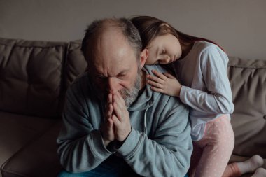 Savaşı durdurun. Ukraynalı endişeli orta yaşlı beyaz adam korkmuş küçük torunu destekliyor. Mutsuz, olgun büyükbaba ve küçük kız evde. Ukrayna için dua et. Ukrayna 'nın yanındayız..