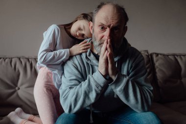 Savaşı durdurun. Ukraynalı endişeli orta yaşlı beyaz adam korkmuş küçük torunu destekliyor. Mutsuz, olgun büyükbaba ve küçük kız evde. Ukrayna için dua et. Ukrayna 'nın yanındayız..