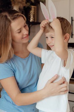Kartondan yapılmış tavşan kulaklı mutlu çocuk. Paskalya Tavşanı Anne ve Çocuk olarak Paskalya bayramını evde birlikte kutluyoruz. Şükran Günü gelenekleri ve çocukluk birlikteliği kavramı. Tatil gelenekleri. Kutlama ve sevinç konsepti.