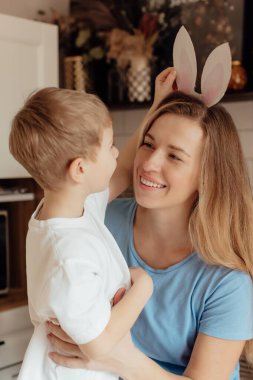 Kartondan yapılmış tavşan kulaklı mutlu çocuk. Paskalya Tavşanı Anne ve Çocuk olarak Paskalya bayramını evde birlikte kutluyoruz. Şükran Günü gelenekleri ve çocukluk birlikteliği kavramı. Tatil gelenekleri. Kutlama ve sevinç konsepti.