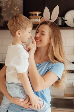 Kartondan yapılmış tavşan kulaklı mutlu çocuk. Paskalya Tavşanı Anne ve Çocuk olarak Paskalya bayramını evde birlikte kutluyoruz. Şükran Günü gelenekleri ve çocukluk birlikteliği kavramı. Tatil gelenekleri. Kutlama ve sevinç konsepti.