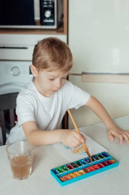 Küçük çocuk Paskalya bayramı için bir kartpostal hazırlıyor. Evde birlikte Paskalya tatili. Şükran Günü gelenekleri ve çocukluk birlikteliği kavramı.