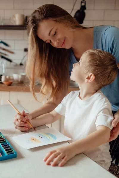Anne ve küçük çocuk Paskalya bayramı için bir kartpostal hazırlıyorlar. Evde birlikte Paskalya tatili. Şükran Günü gelenekleri ve çocukluk birlikteliği kavramı.