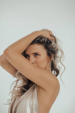 Stüdyoda parlak bir arka planda poz veren altın elbiseli güzel sarışın kız. Kadın vücudu ve tarz kavramı. Reklam ya da kıyafet satışı tasarımı.