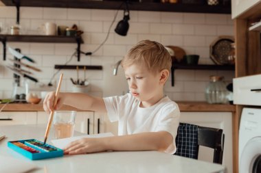 Küçük çocuk Paskalya bayramı için bir kartpostal hazırlıyor. Evde birlikte Paskalya tatili. Şükran Günü gelenekleri ve çocukluk birlikteliği kavramı.