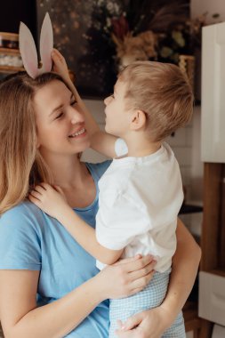 Kartondan yapılmış tavşan kulaklı mutlu çocuk. Paskalya Tavşanı Anne ve Çocuk olarak Paskalya bayramını evde birlikte kutluyoruz. Şükran Günü gelenekleri ve çocukluk birlikteliği kavramı. Tatil gelenekleri. Kutlama ve sevinç konsepti.