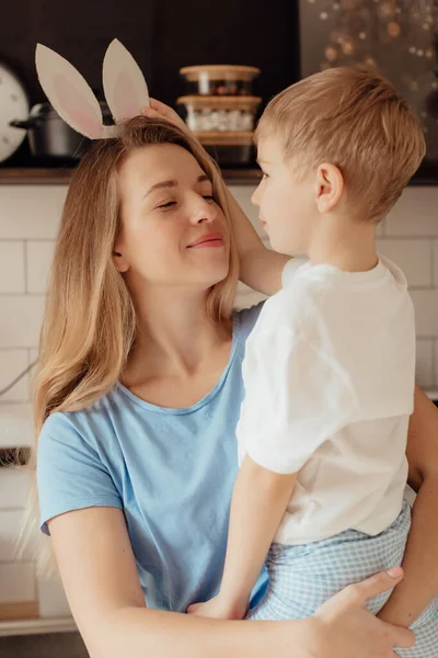 Kartondan yapılmış tavşan kulaklı mutlu çocuk. Paskalya Tavşanı Anne ve Çocuk olarak Paskalya bayramını evde birlikte kutluyoruz. Şükran Günü gelenekleri ve çocukluk birlikteliği kavramı. Tatil gelenekleri. Kutlama ve sevinç konsepti.