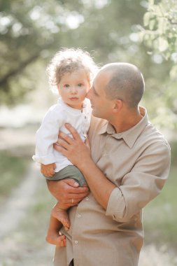Buğday tarlasında çocuklu mutlu bir genç adam. Mutlu babalar. Macera, seyahat, turizm, yürüyüş ve insan konsepti - mutlu aile yürüyüşleri