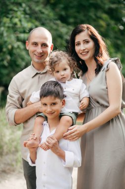 Buğday tarlasında iki çocuklu mutlu bir aile. Macera, seyahat, turizm, yürüyüş ve insan konsepti - mutlu aile yürüyüşleri