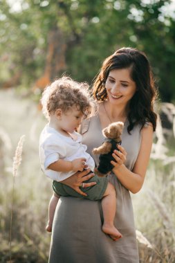 Buğday tarlasında çocuklu mutlu bir genç kadın. Mutlu annelikler. Macera, seyahat, turizm, yürüyüş ve insan konsepti - mutlu aile yürüyüşleri