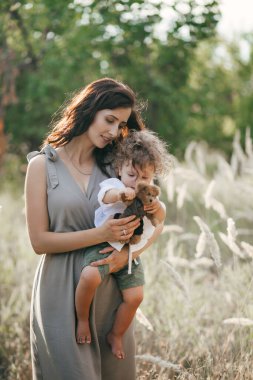 Buğday tarlasında çocuklu mutlu bir genç kadın. Mutlu annelikler. Macera, seyahat, turizm, yürüyüş ve insan konsepti - mutlu aile yürüyüşleri