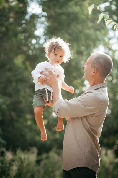 Buğday tarlasında çocuklu mutlu bir genç adam. Mutlu babalar. Macera, seyahat, turizm, yürüyüş ve insan konsepti - mutlu aile yürüyüşleri