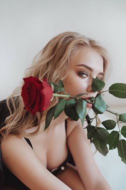 Kırmızı güllü güzel sarışın kız modeli. Aydınlık arka planda Spring Lady. Kadın güzelliği ve tarz kavramı. Reklam ya da kıyafet satışı tasarımı.