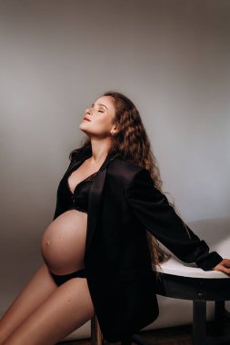 Yakından siyah elbiseli güzel, hamile bir kadın. İç çamaşırlı seksi manken kız portresi. Kapalı mekanlarda çekici vücudu olan güzel, şehvetli bir kadın. Yaklaşan kadın göbeği.