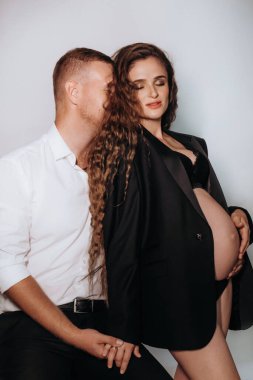 Yakından siyah elbiseli güzel, hamile bir kadın. Aşık seksi moda çifti portresi. Güzel, şehvetli bir kadın ve içeride bir erkek. Yaklaşan kadın göbeği.