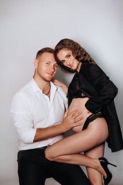 Yakından siyah elbiseli güzel, hamile bir kadın. Aşık seksi moda çifti portresi. Güzel, şehvetli bir kadın ve içeride bir erkek. Yaklaşan kadın göbeği.