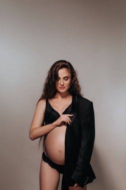 Yakından siyah elbiseli güzel, hamile bir kadın. İç çamaşırlı seksi manken kız portresi. Kapalı mekanlarda çekici vücudu olan güzel, şehvetli bir kadın. Yaklaşan kadın göbeği.