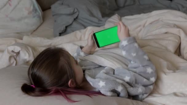 Little Girl Holding Mobile Smartphone Chromakey Green Screen Bed Tew — Stockvideo