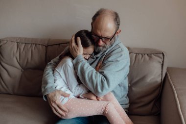 Ukraynalı endişeli orta yaşlı beyaz adam korkmuş küçük torunu destekliyor. Mutsuz, olgun büyükbaba ve küçük kız evde. Stres ve korku kavramı