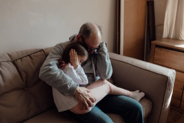 Ukraynalı endişeli orta yaşlı beyaz adam korkmuş küçük torunu destekliyor. Mutsuz, olgun büyükbaba ve küçük kız evde. Stres ve korku kavramı