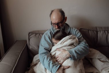 Ukraynalı endişeli orta yaşlı beyaz adam korkmuş küçük torunu destekliyor. Mutsuz, olgun büyükbaba ve küçük kız evde. Stres ve korku kavramı