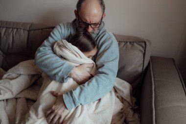 Ukraynalı endişeli orta yaşlı beyaz adam korkmuş küçük torunu destekliyor. Mutsuz, olgun büyükbaba ve küçük kız evde. Stres ve korku kavramı