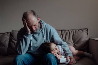 Ukraynalı endişeli orta yaşlı beyaz adam korkmuş küçük torunu destekliyor. Mutsuz, olgun büyükbaba ve küçük kız evde. Stres ve korku kavramı