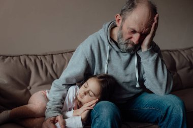 Ukraynalı endişeli orta yaşlı beyaz adam korkmuş küçük torunu destekliyor. Mutsuz, olgun büyükbaba ve küçük kız evde. Stres ve korku kavramı