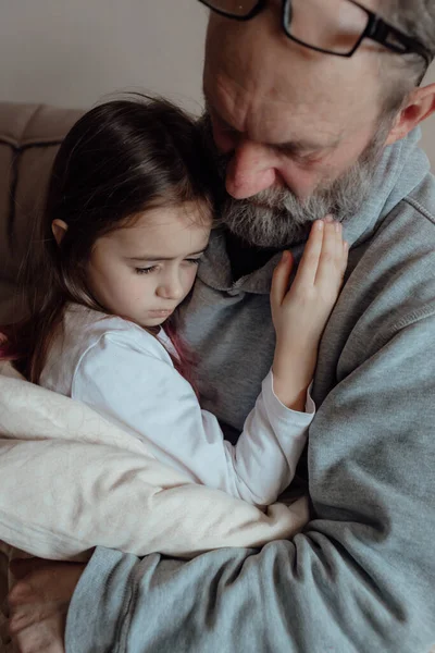 Ukraynalı endişeli orta yaşlı beyaz adam korkmuş küçük torunu destekliyor. Mutsuz, olgun büyükbaba ve küçük kız evde. Stres ve korku kavramı