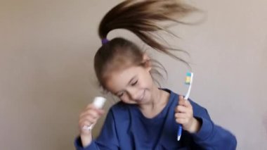 Şirin küçük kız banyoda dişlerini fırçaladı. Kız, diş fırçası ve diş macunuyla dans ederken yemek yemiş. Kameraya bakıyorum..