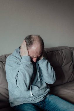 Ukraynalı endişeli orta yaşlı adam yüksek sesten korktu ve korkudan kulaklarını kapattı. Mutsuz olgun büyükbaba evde..