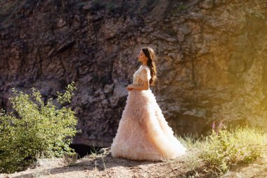 Kayalardan oluşan bir arka planda Boho tarzı elbise giyen modaya uygun genç bir manken. Kadın güzelliği ve tarz kavramı. Reklam ya da kıyafet satışı tasarımı.