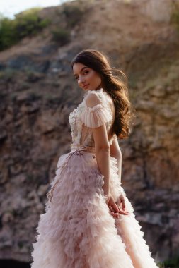 Kayalardan oluşan bir arka planda Boho tarzı elbise giyen modaya uygun genç bir manken. Kadın güzelliği ve tarz kavramı. Reklam ya da kıyafet satışı tasarımı.